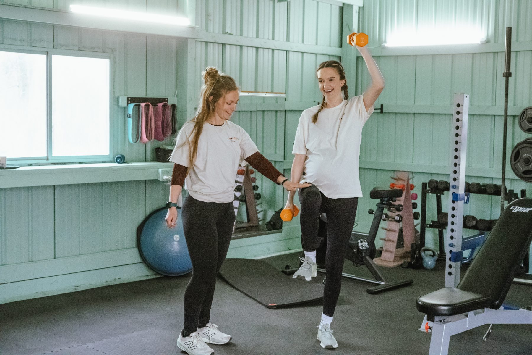 Jess coaching a pregnant client through a dumbbell exercise