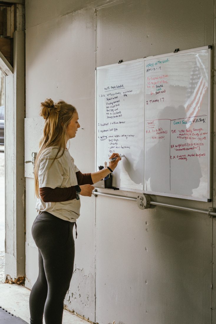 Jess writing the week's programming and client wins on the gym whiteboard